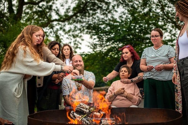 Group gathered around an outdoor fire ceremony among trees
