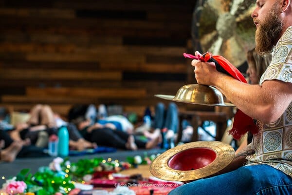 Sound healing session in a wood-panelled studio with participants resting on mats